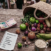 High-angle of fresh Nigerian vegetables, rice, bananas, and Naira notes on a wooden market table purchased using market hacks