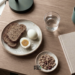 Flat lay of eggs and toast on a desk beside a notebook before a morning meeting