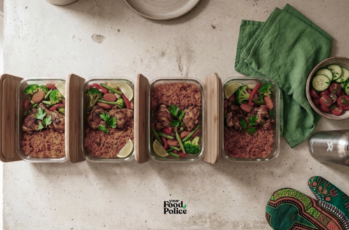 Flat-lay of jollof rice and grilled chicken meal prep containers on a kitchen counter