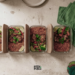 Flat-lay of jollof rice and grilled chicken meal prep containers on a kitchen counter