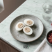 Overhead angle of three halved hard-boiled eggs with pepper and salt on a ceramic plate, surrounded by diced vegetables and a water glass.