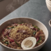 Overhead shot of Indomie with vegetables and a hard-boiled egg next to a fork on a stone counter